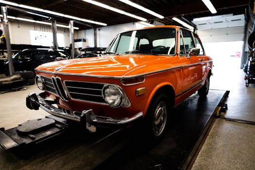 Vibrant orange vintage BMW car in a mechanic's shop, highlighting its timeless design.