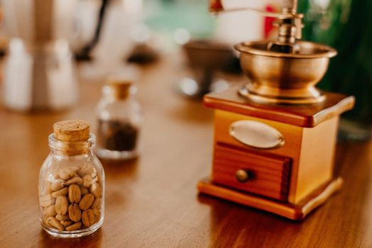 Old-fashioned coffee grinder with coffee beans in a jar on a wooden table.
