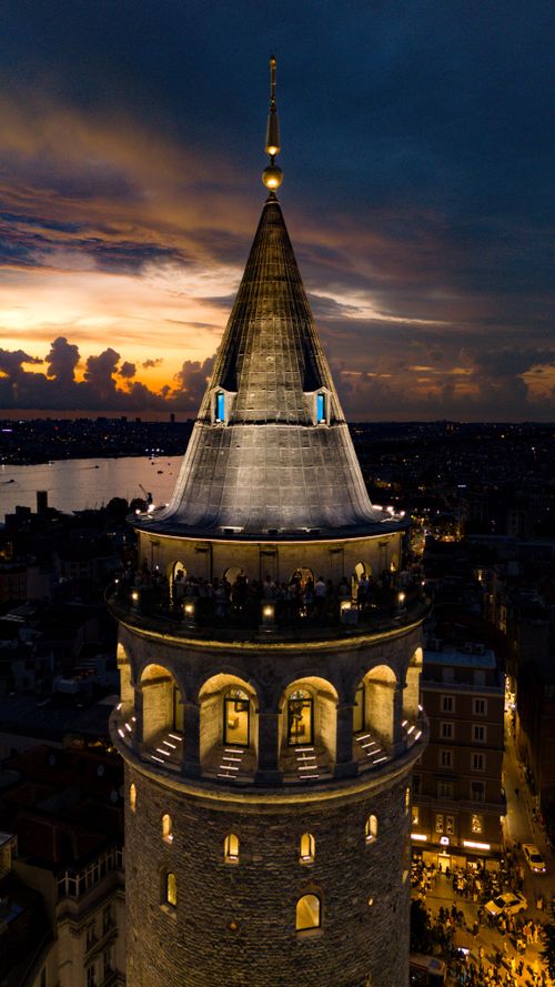 Free A stunning aerial view of Galata Tower lit up against a dramatic evening sky. Stock Photo