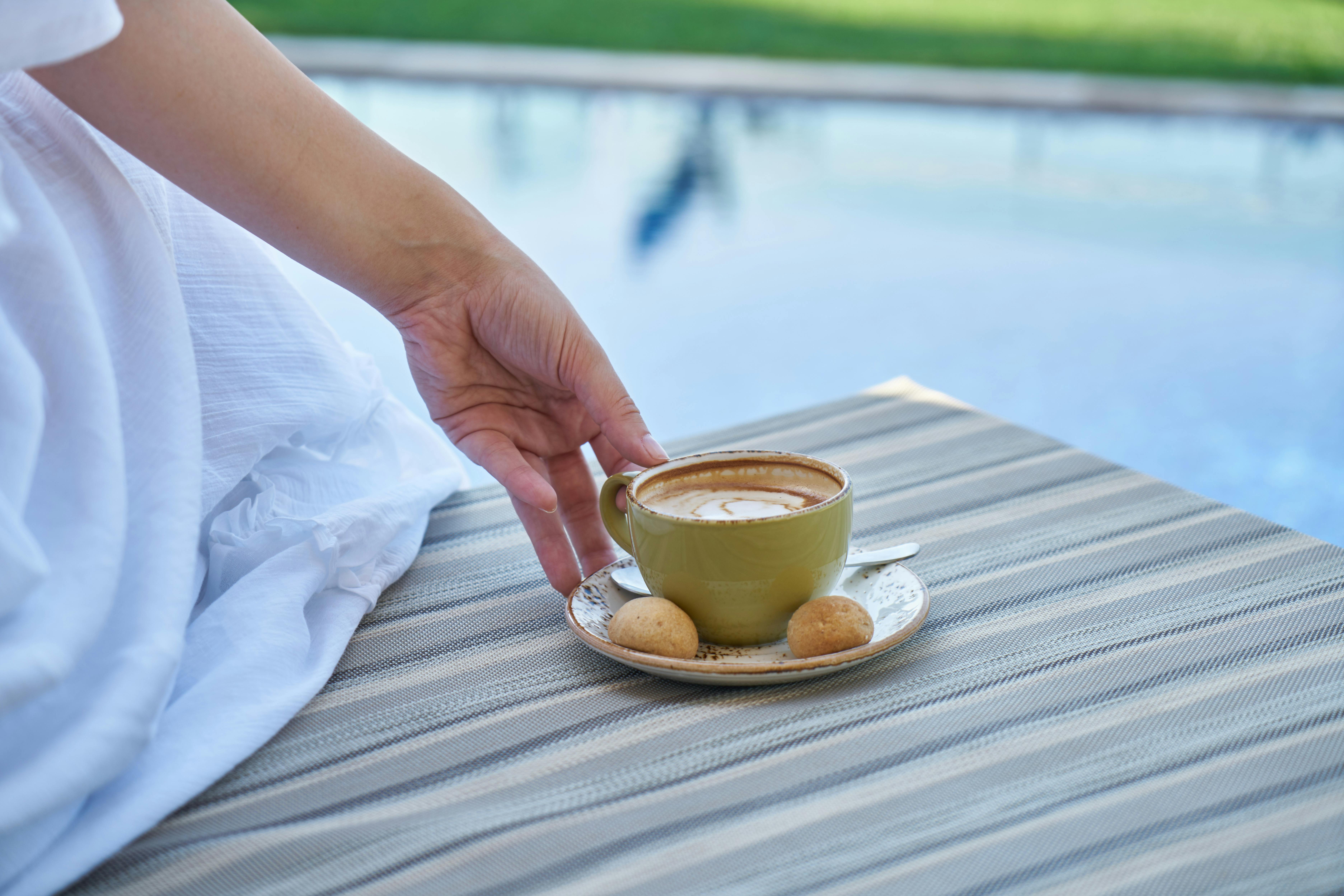 person holding cup of coffee with saucer