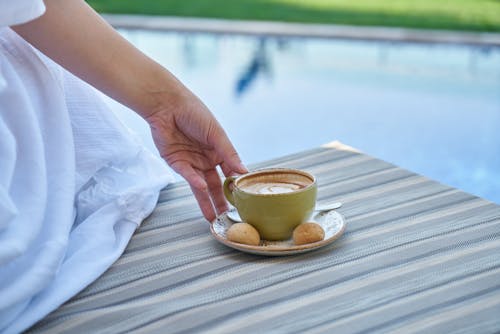 Person Holding Cup of Coffee With Saucer