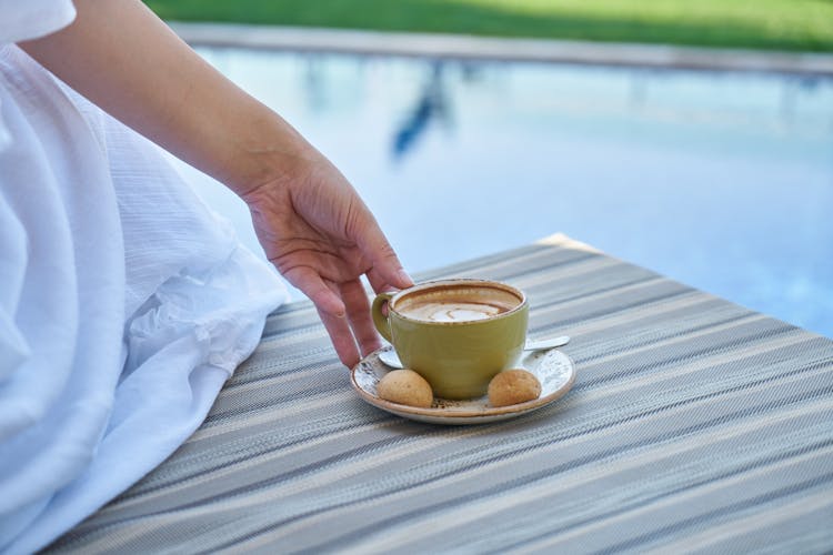 Person Holding Cup Of Coffee With Saucer