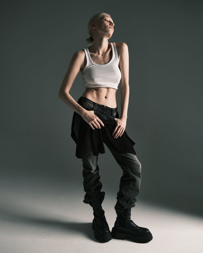 Mannequin en top blanc et pantalon gris dans un studio