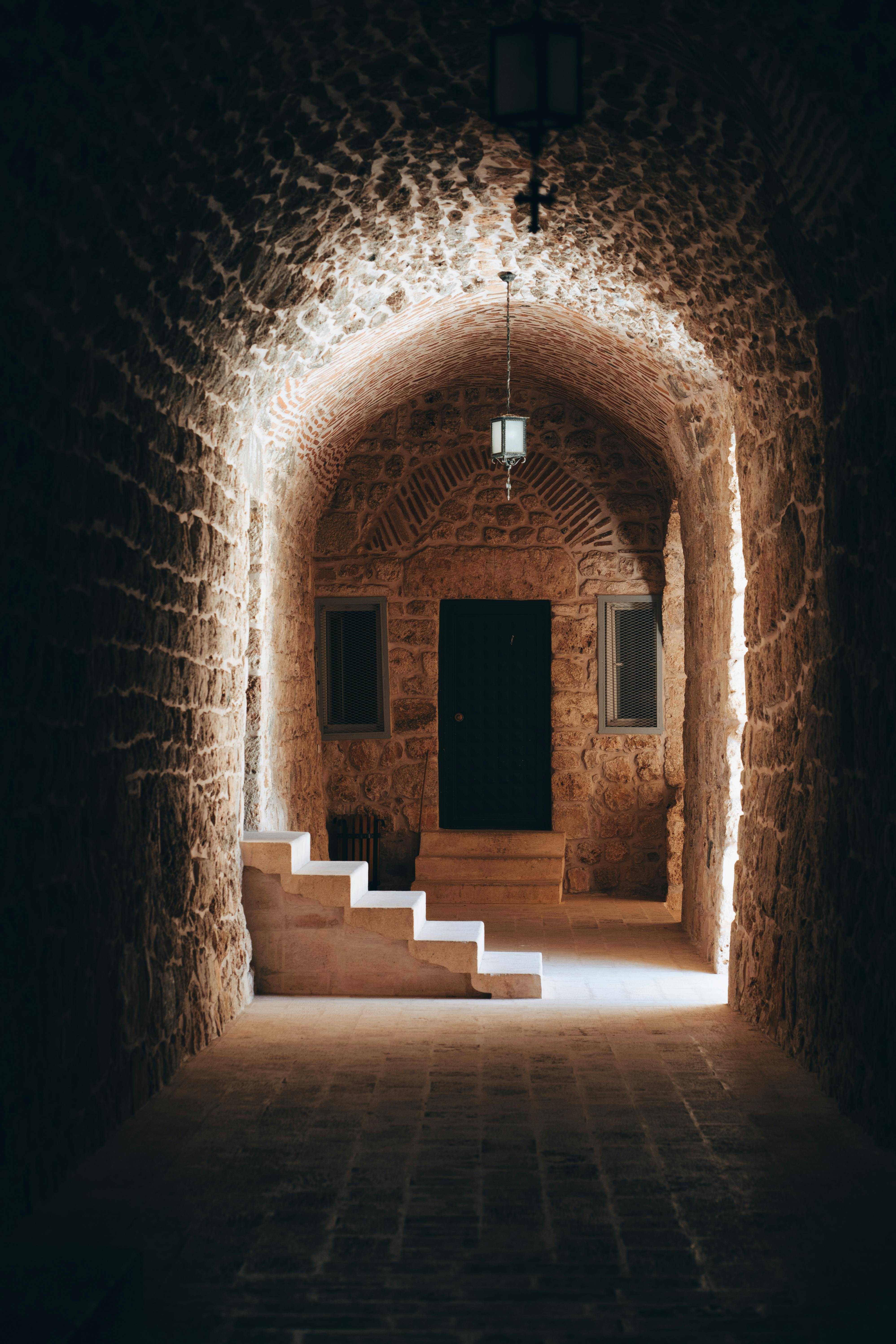 A serene stone archway inside an ancient monastery in Midyat, Mardin, Türkiye, showcasing intricate masonry.