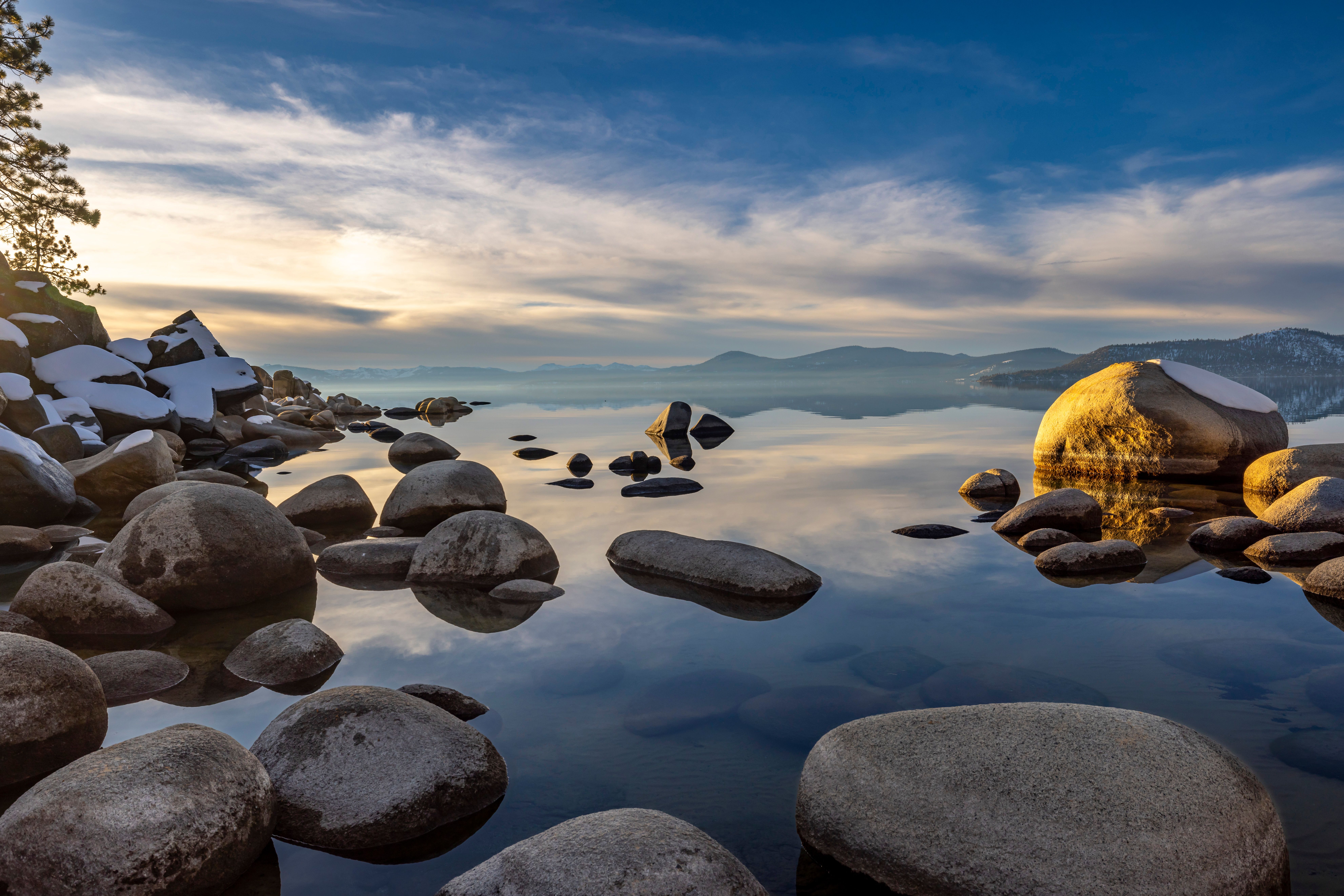 Scenic view of a rocky lake shore with reflections on a calm day in winter.