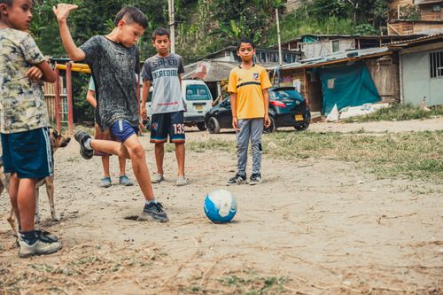 Free Children playing street soccer near homes, showcasing urban community life. Stock Photo
