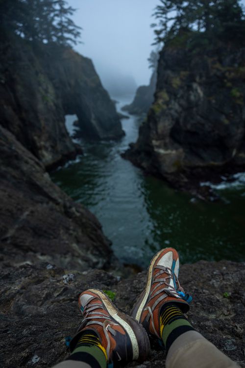 Free Hiker's boots resting on cliff edge overlooking misty rocky gorge and river. Stock Photo