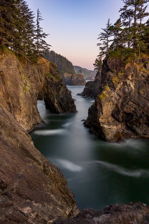 Free A tranquil coastal scene featuring dramatic cliffs and a calm sea at dawn, creating a peaceful atmosphere. Stock Photo