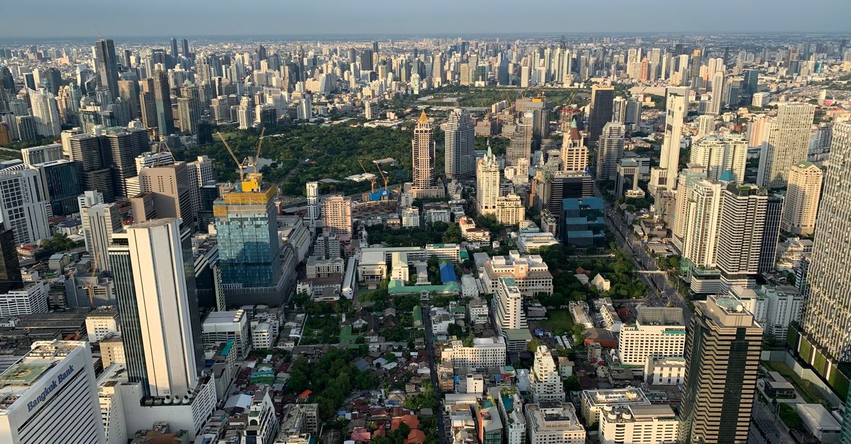 Stunning aerial view of Bangkok skyline with skyscrapers and urban greenery.