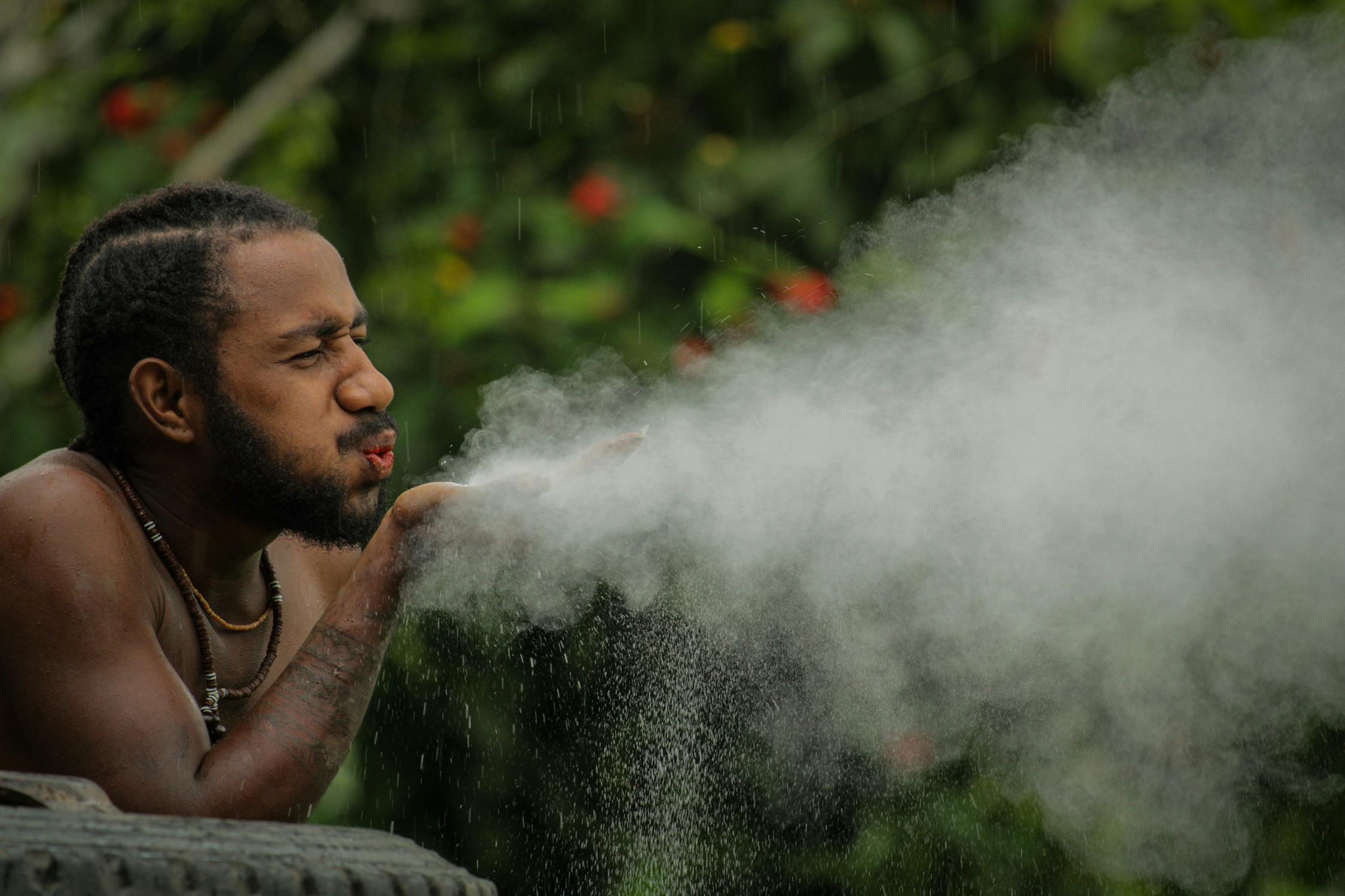 Man Blowing Powder Outdoors in Natural Setting · Free Stock Photo
