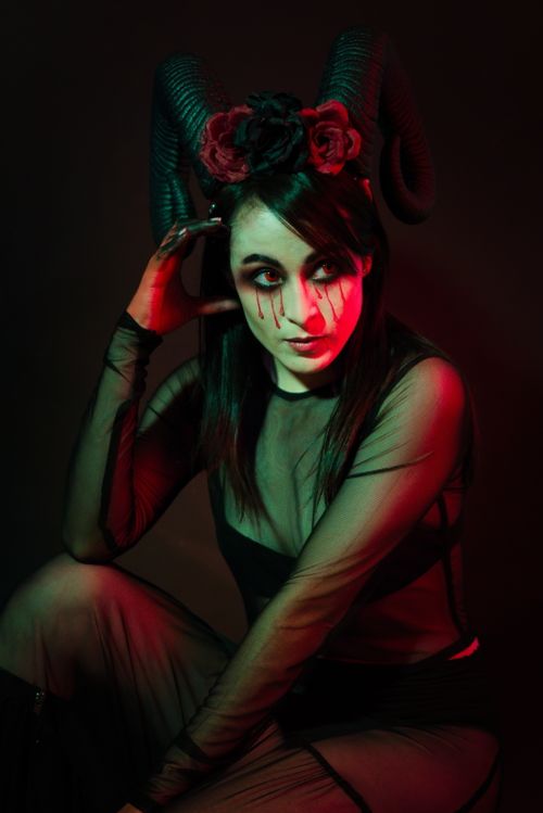 Free Artistic portrait of a woman in costume with horns and face paint under dramatic lighting. Stock Photo