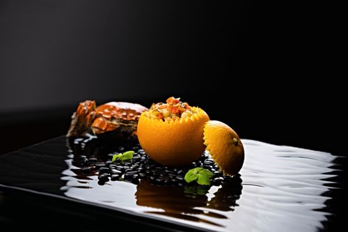 Free Elegant gourmet dish featuring fresh crab meat served in an orange shell with a black background. Stock Photo