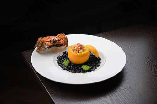 Free A gourmet seafood presentation featuring a crab and citrus garnish on a bed of black beans. Stock Photo