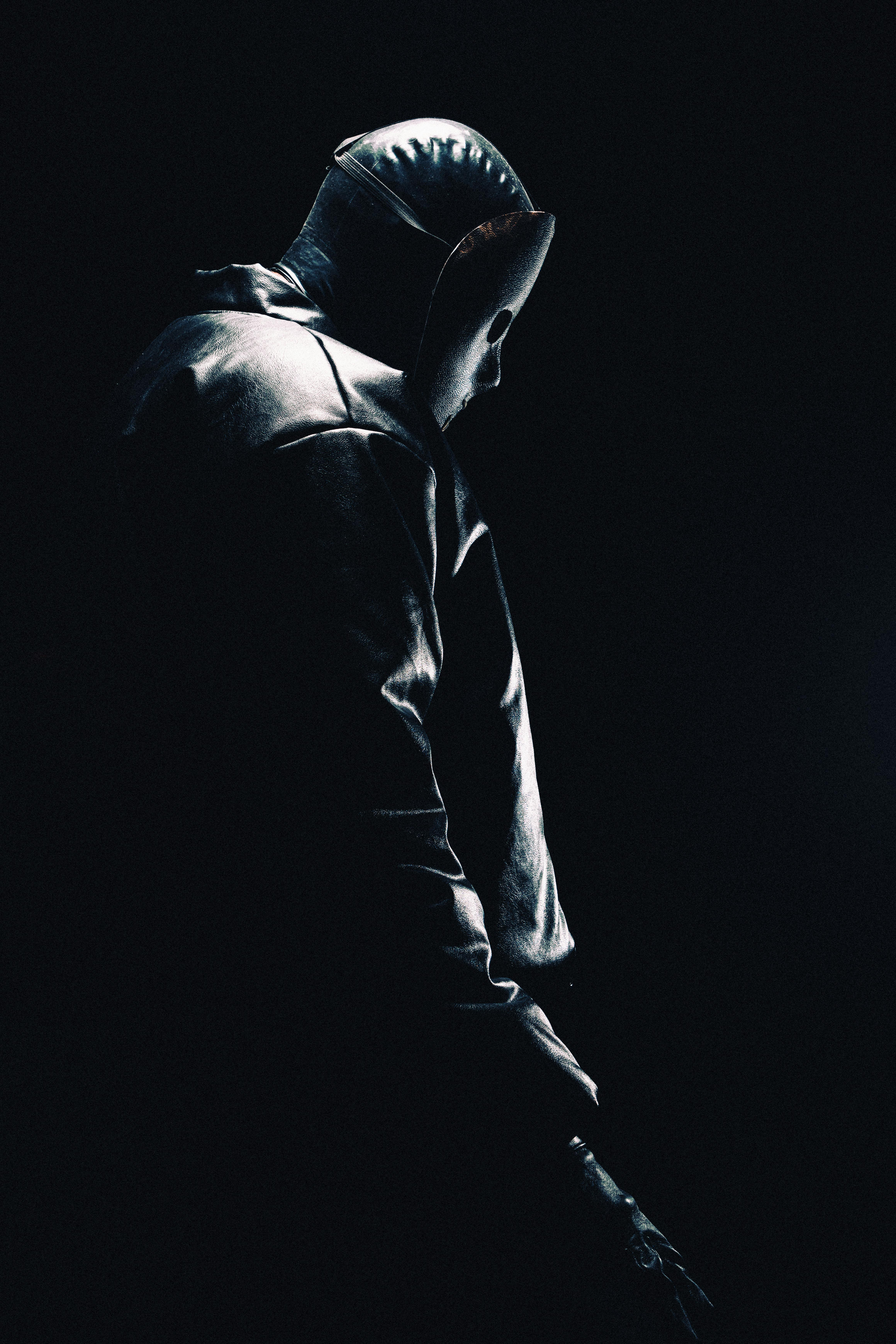 Moody silhouette of a hooded person in darkness, evoking mystery.