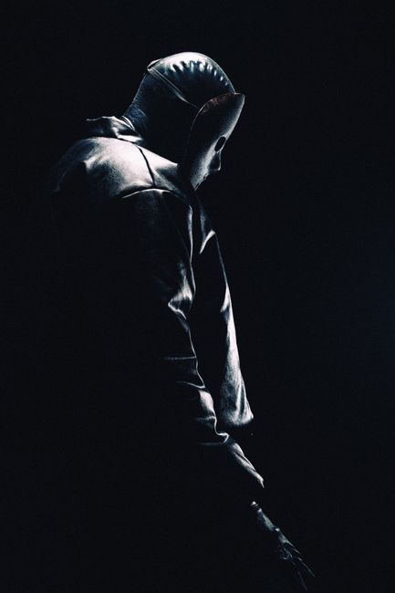 Moody silhouette of a hooded person in darkness, evoking mystery.
