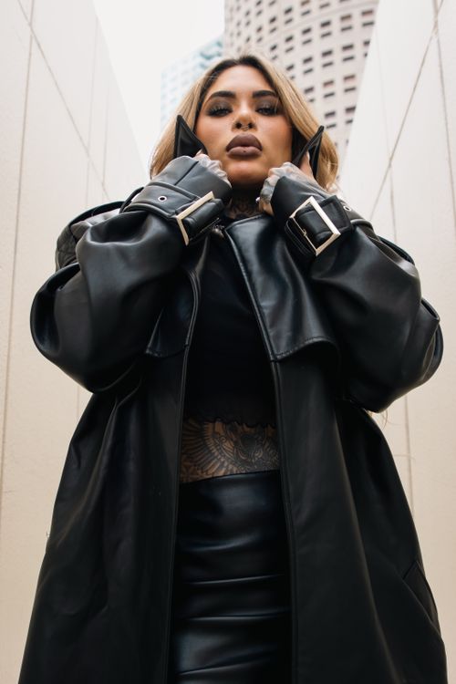 Free Confident woman in stylish leather jacket posing in city alley. Stock Photo