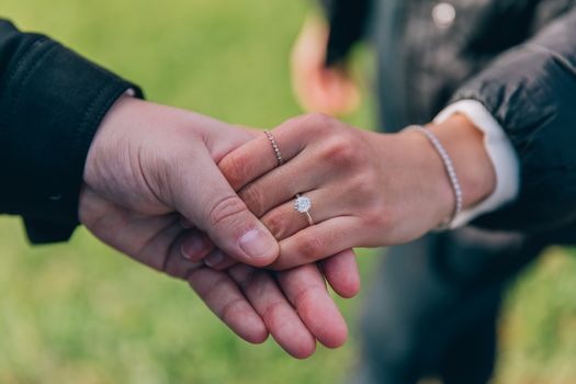 Close-up of hands holding with an engagement ring in an outdoor setting, Campbelltown, NSW.
