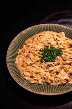 Close-up of creamy pasta topped with fresh chives, highlighting a gourmet culinary delight.