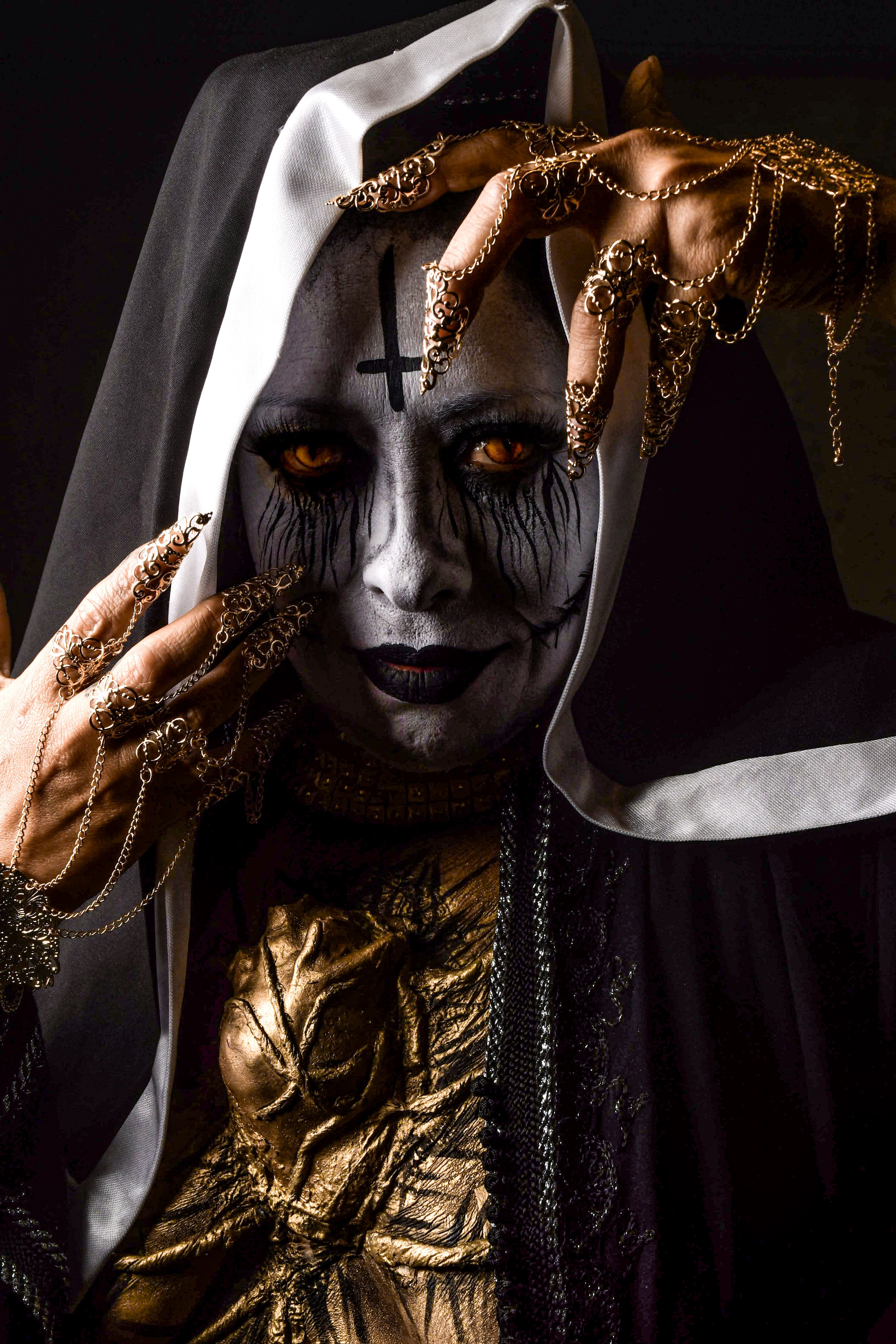A person in Gothic makeup with chains draped over hands, evoking mystery and darkness.
