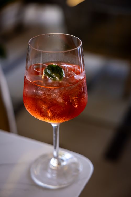Free A refreshing glass of iced Aperol Spritz with mint garnish in a cozy setting. Stock Photo