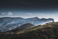 黄昏的天空下，宁静的山地景观中有一座塔楼和云雾