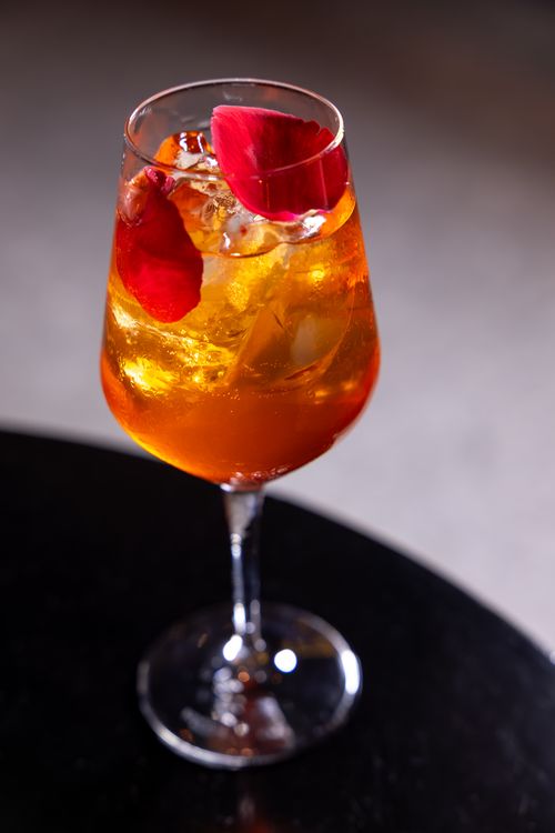 Free A stylish orange cocktail garnished with vibrant flower petals in a glass. Stock Photo
