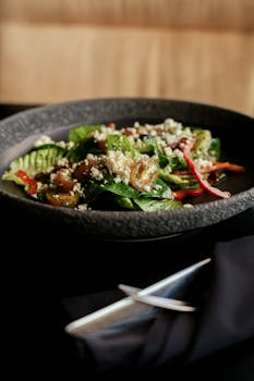 Delicious quinoa salad with fresh vegetables in a black bowl, perfect for a healthy meal.