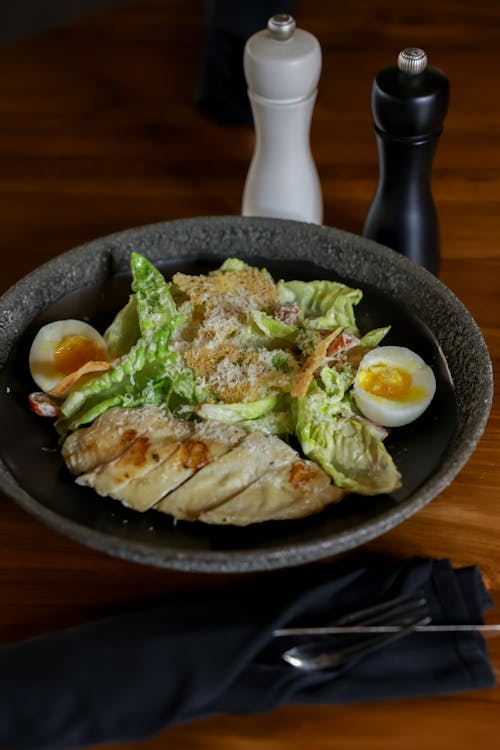 Free Scrumptious Caesar salad with grilled chicken, eggs, on rustic table setting. Stock Photo