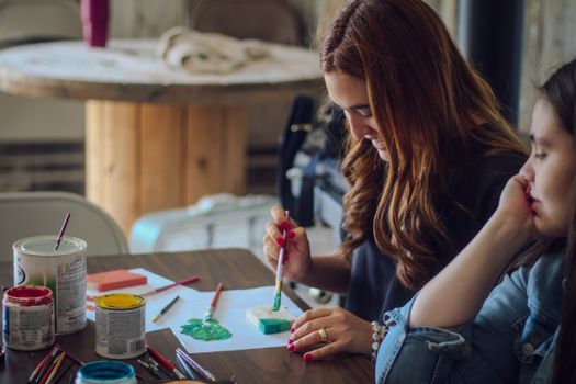 Two women engage in a creative painting activity, focused on art and expression.