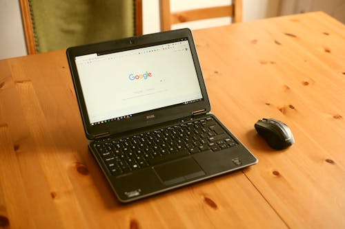 Free Black Laptop Computer and Wireless Mouse on Table Stock Photo