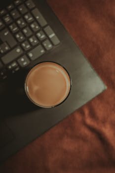 Top view of coffee cup on laptop, minimalist and serene workspace in Aracati, Brazil.