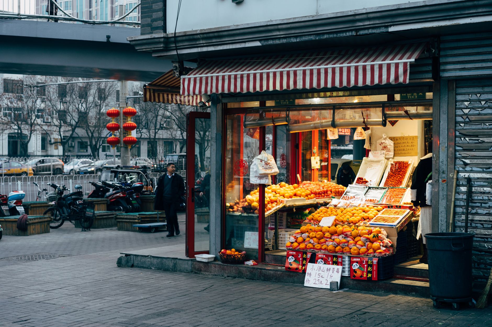 Vibrant street fruit market in Beijing with lanterns and pedestrians at dusk.