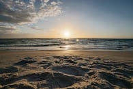 宁静的日落映照着沙滩和温柔的海浪，捕捉了海景的静谧