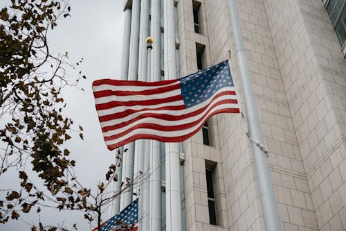 Free Low angle of American flag waving in front of a government building in Anaheim, CA. Stock Photo