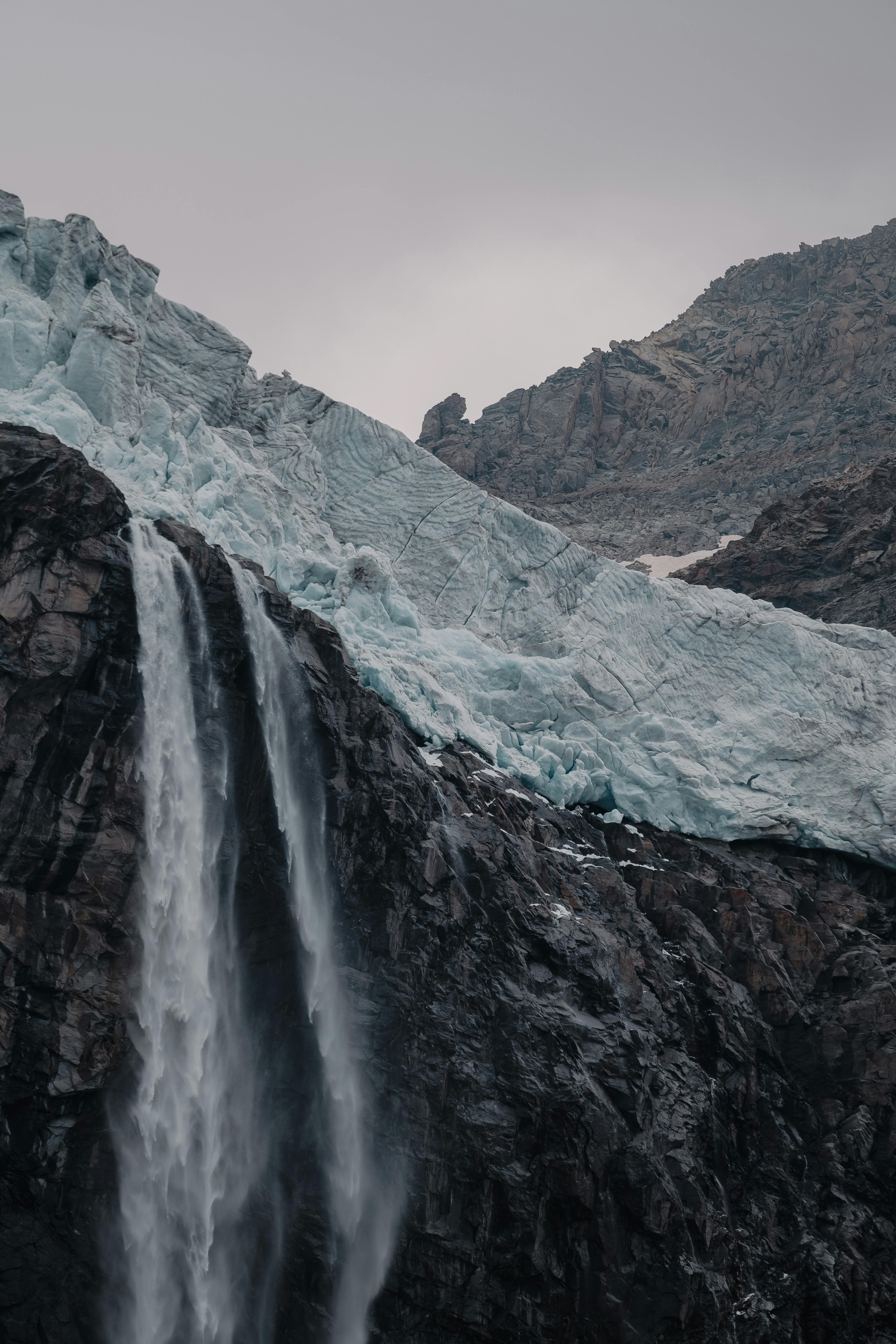 Stunning view of a glacier and waterfall amidst rugged mountains, exuding natural serenity.