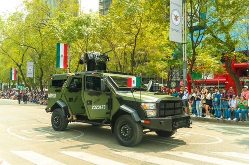 Free An armored military vehicle in Mexico City's parade, featuring Mexican flags and spectators. Stock Photo