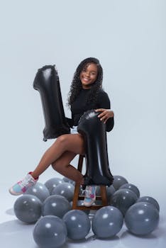 Happy teenager celebrating birthday with balloons indoors.