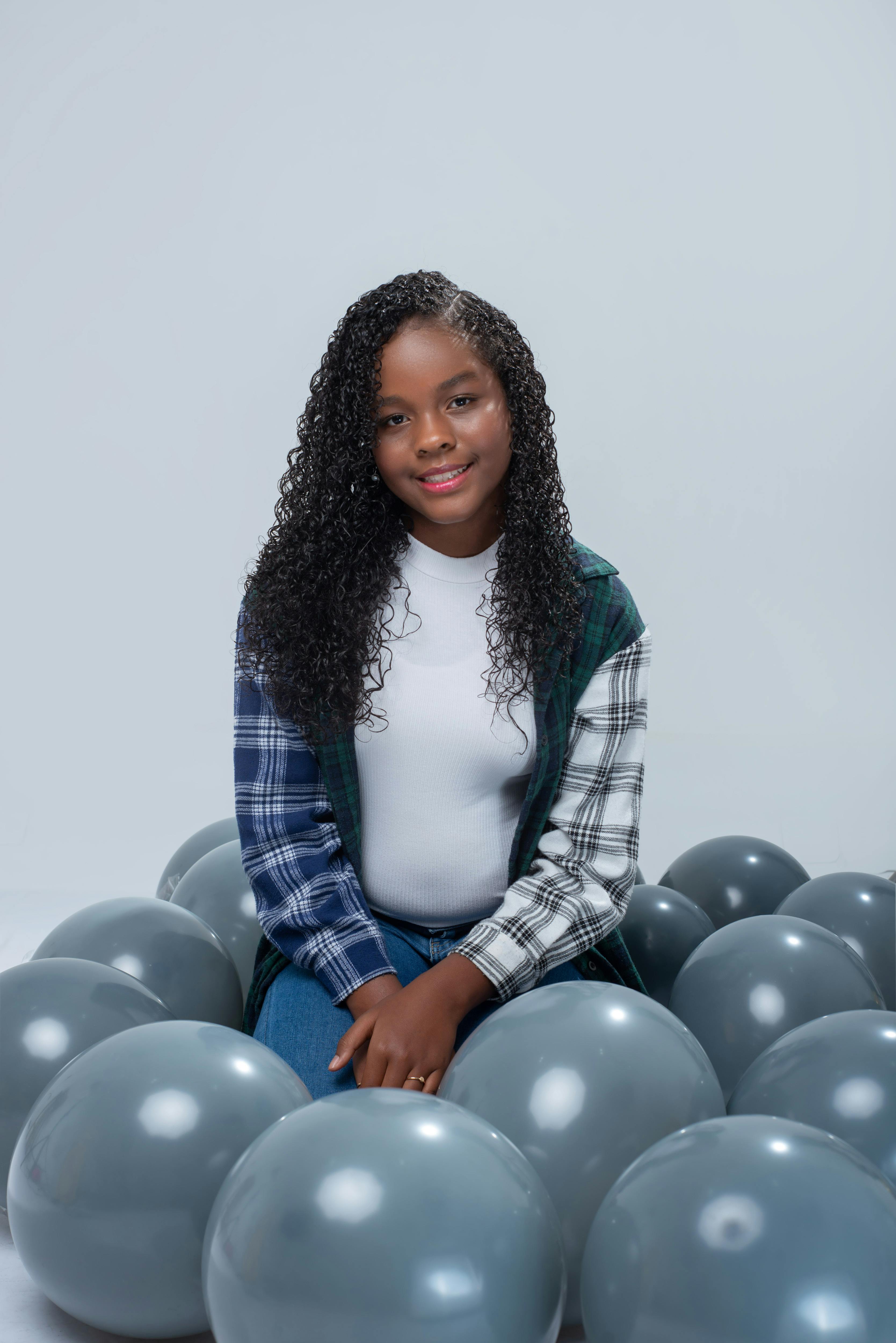 young woman sitting among balloons in studio