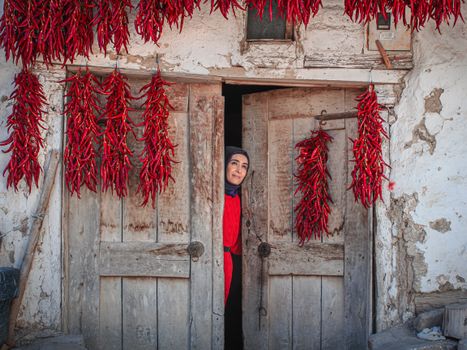 Woman Peeking Through Rustic Doorway with Red Peppers