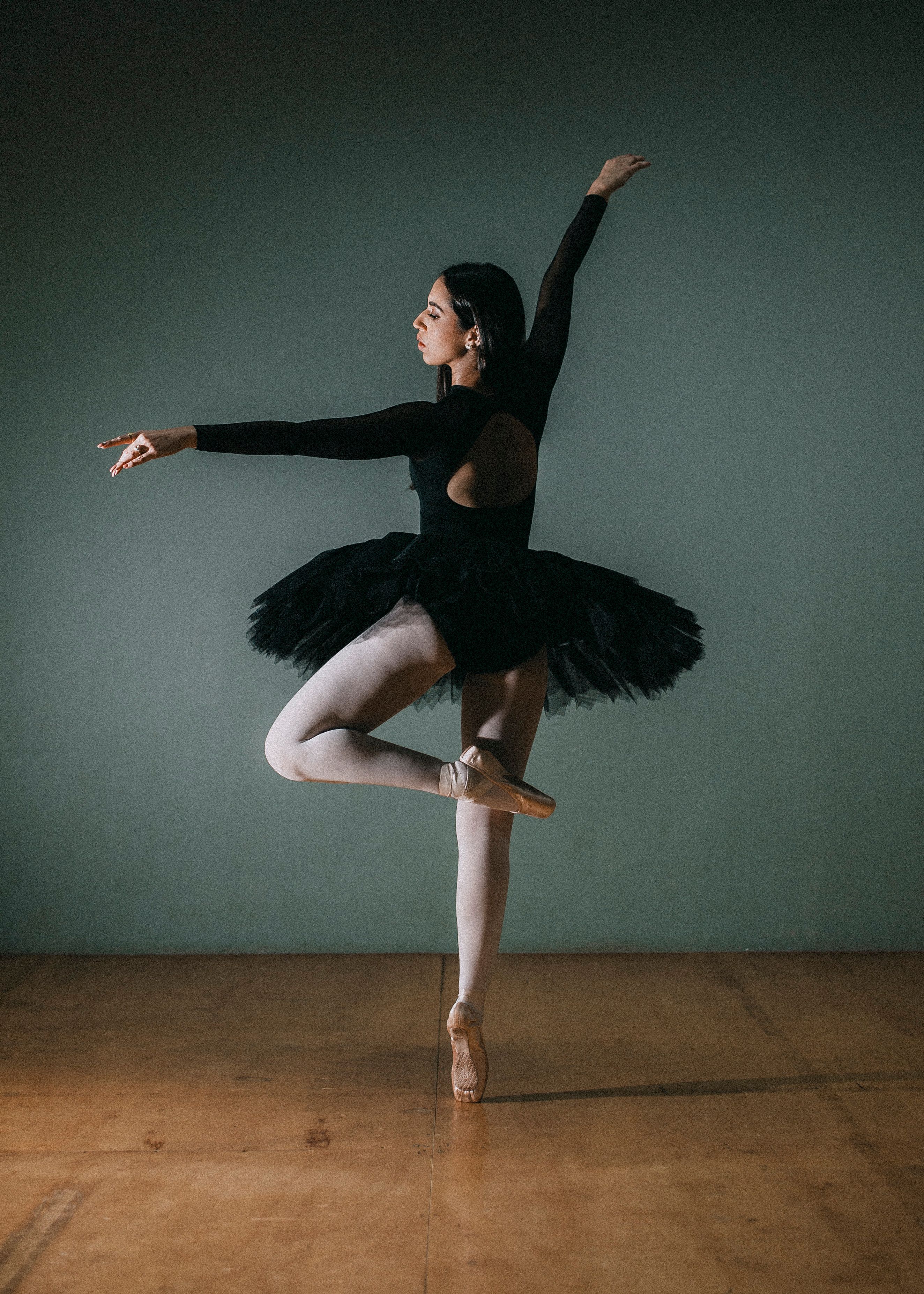 Graceful ballet dancer poses in a studio wearing a black costume, showcasing poise and elegance.