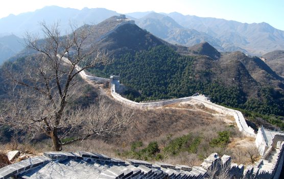 A breathtaking view of the Great Wall of China snaking through rugged mountainous terrain seen in daylight.
