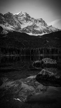 Serene black and white landscape of Zugspitze mountain reflected in Eibsee Lake, Bavaria, Germany.