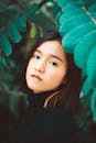 一幅描绘迷人亚洲女性的肖像画，被充满活力的绿叶环绕，展现出美丽与宁静