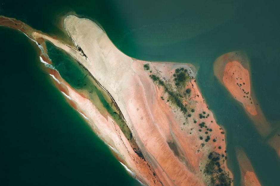 Stunning aerial view of sandbanks with lush vegetation surrounded by tranquil green waters.