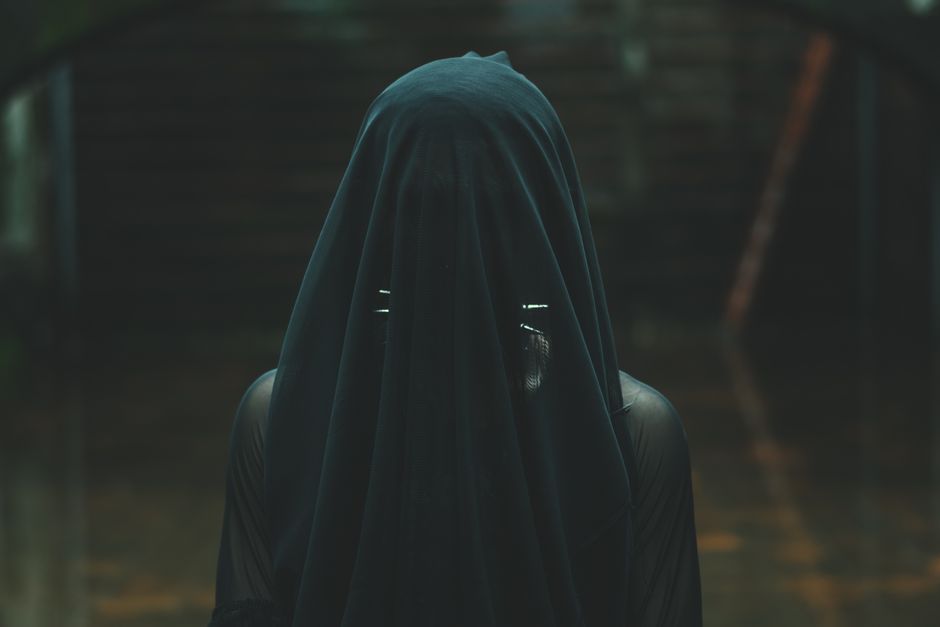 Intriguing image of a person draped in a dark veil, evoking mystery and fashion.