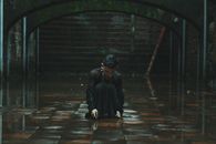 在雨中的城市里，一个身着黑色连衣裙的人跪着，唤起了一种内省的感觉