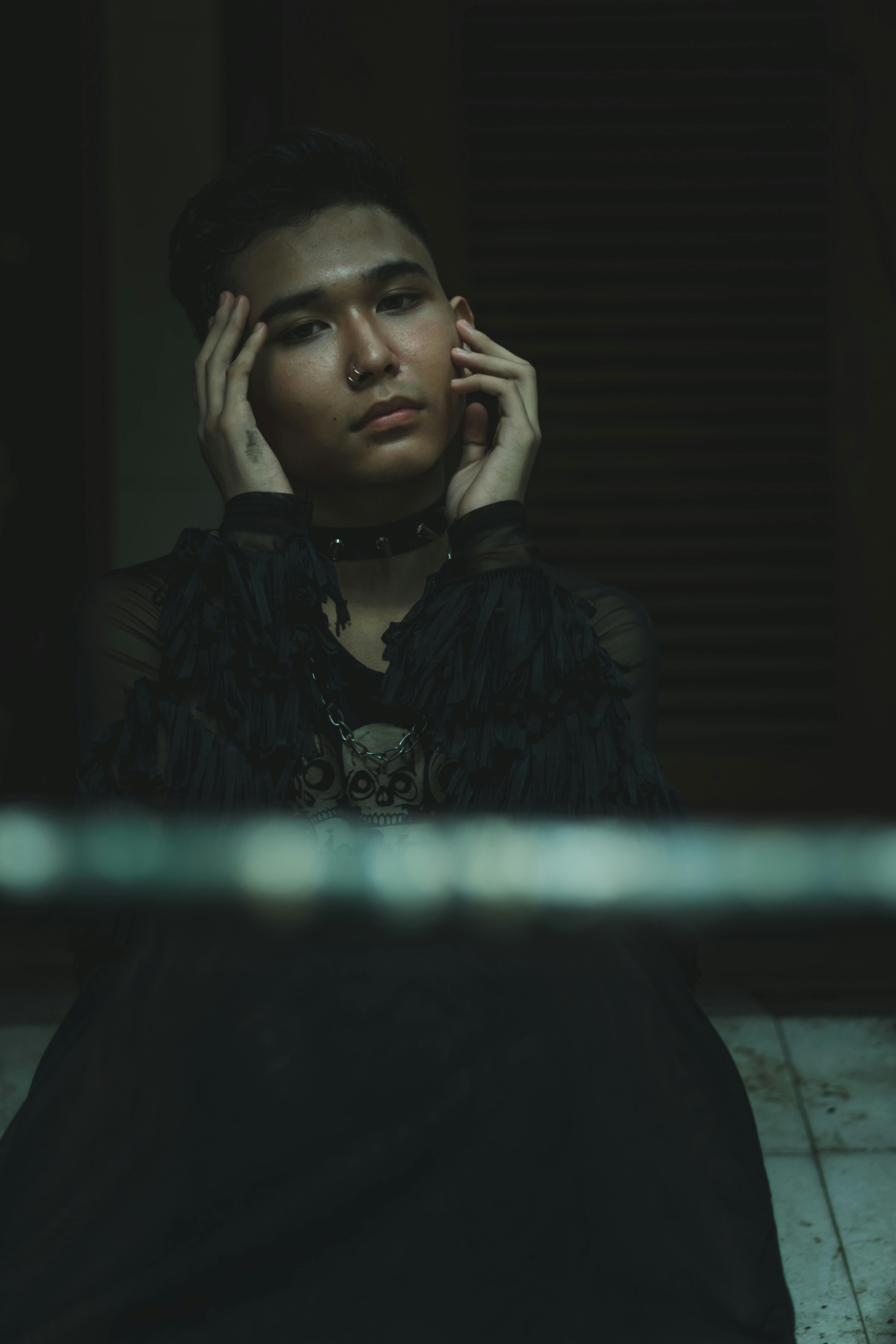 Stylish young man with nose ring in a contemplative pose indoors.