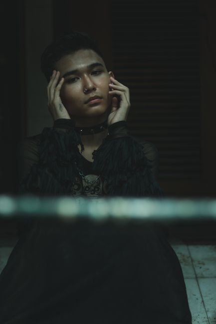 Stylish young man with nose ring in a contemplative pose indoors.