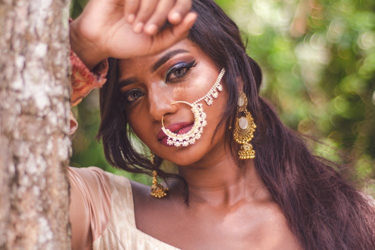 Selective Focus Close-up Portrait Photo Of Indian Woman With Nose Ring Posing By Tree