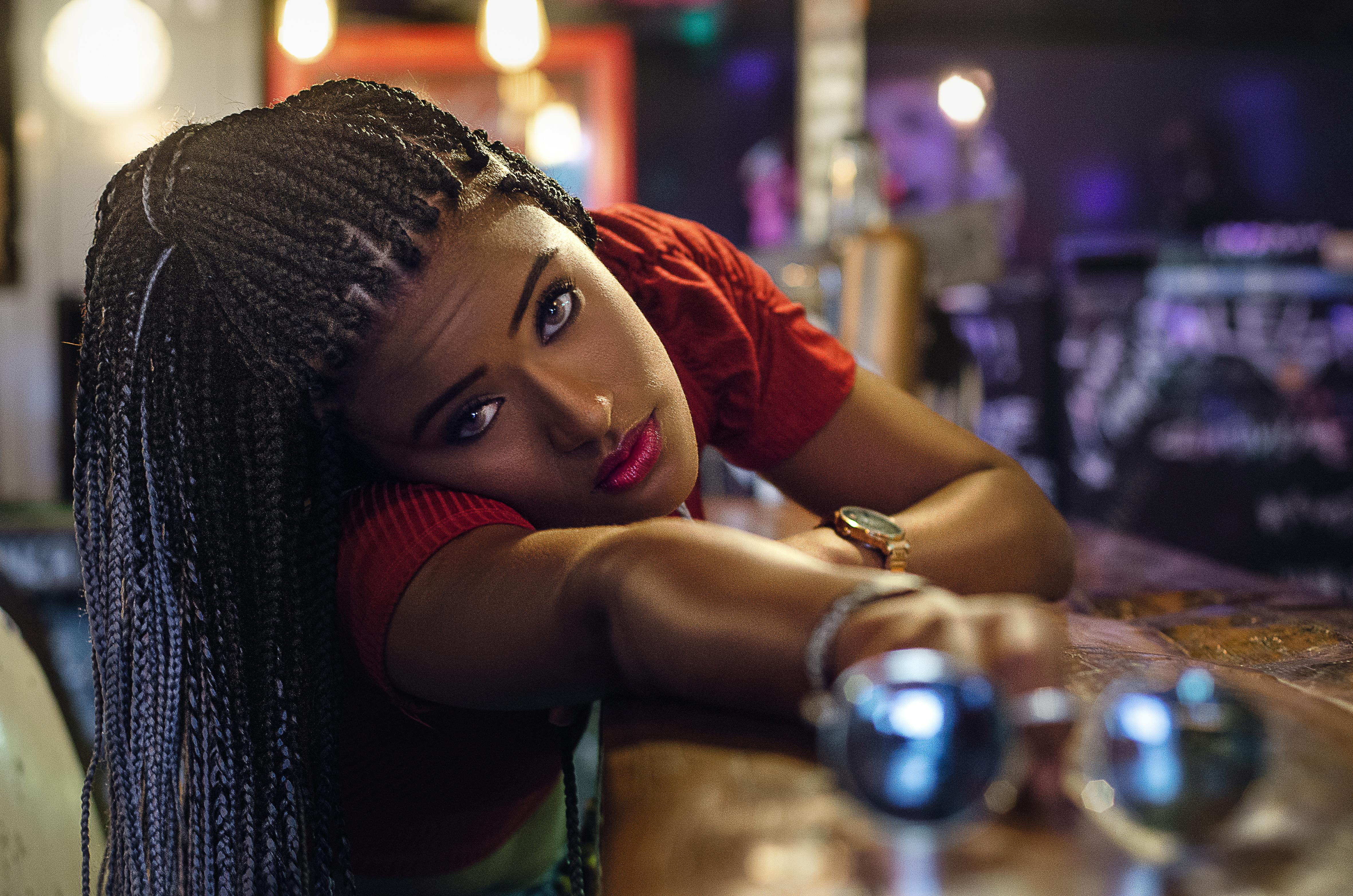 一位梳着辫子的时尚女性，在室内温暖的灯光下摆出姿势，尽显时尚与优雅